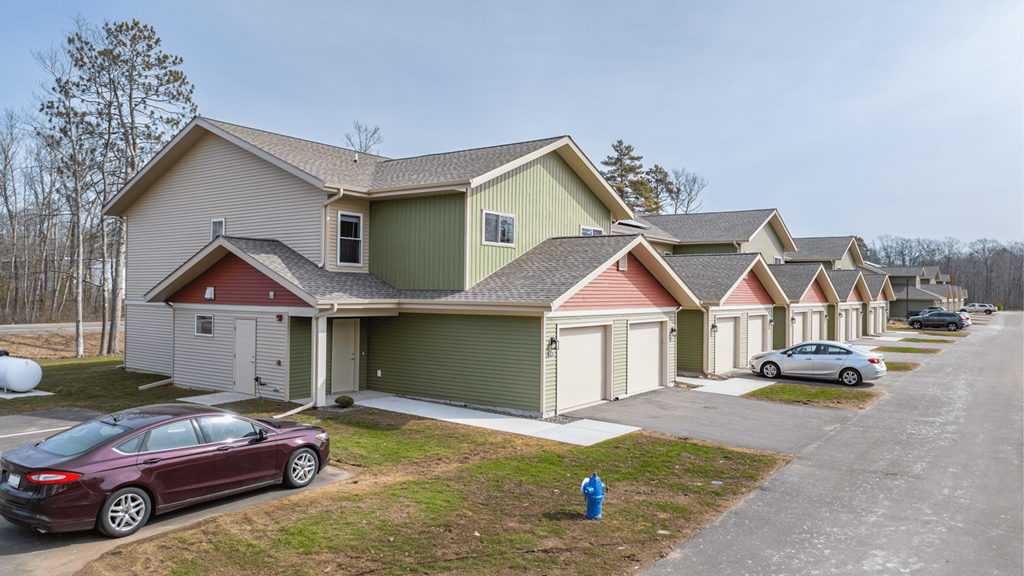 A row of houses with cars parked in front.