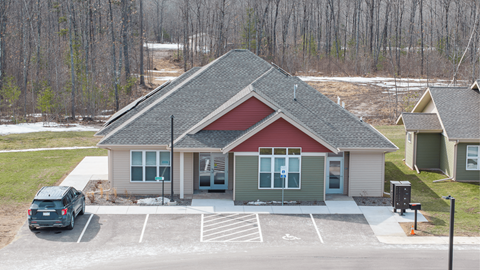 A small building with a red roof is surrounded by a parking lot.