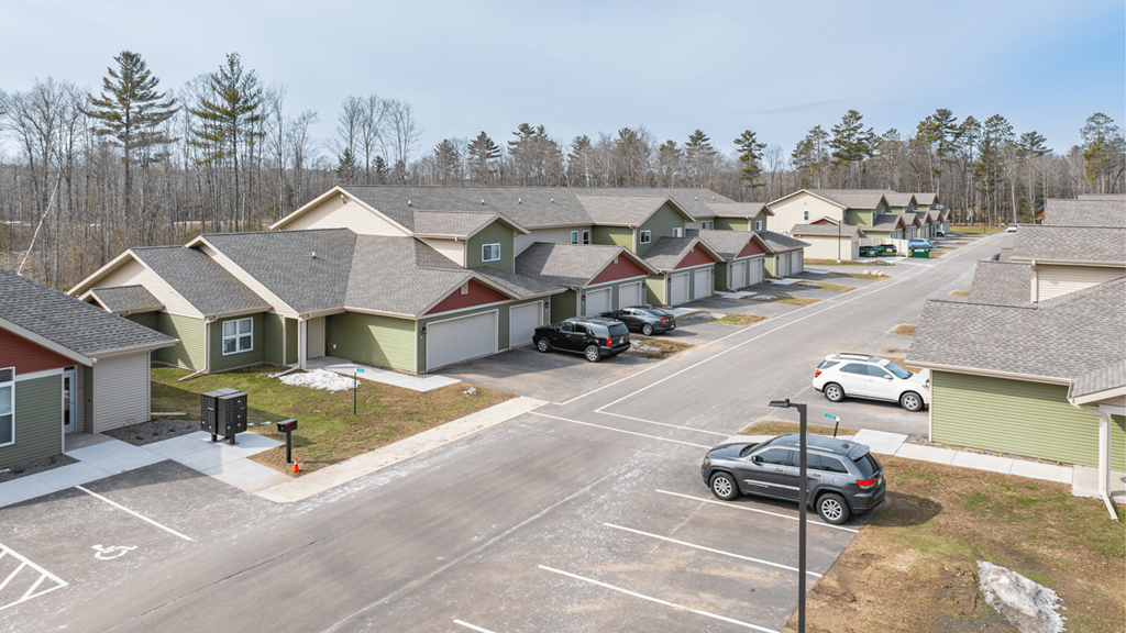 A parking lot with cars and houses in the background.