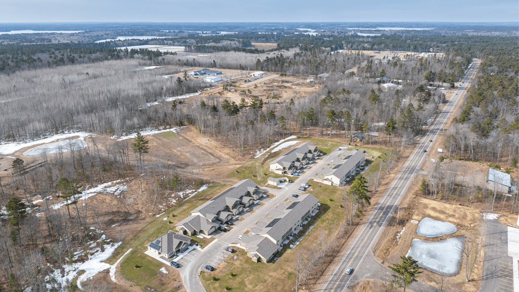 An aerial view of a parking lot and buildings with a road running through the middle.