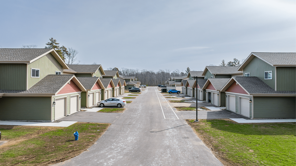 A row of houses with a person walking a dog on the sidewalk.
