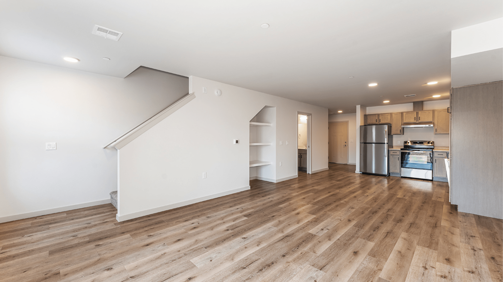 A spacious room with wooden flooring and a staircase leading to another level.