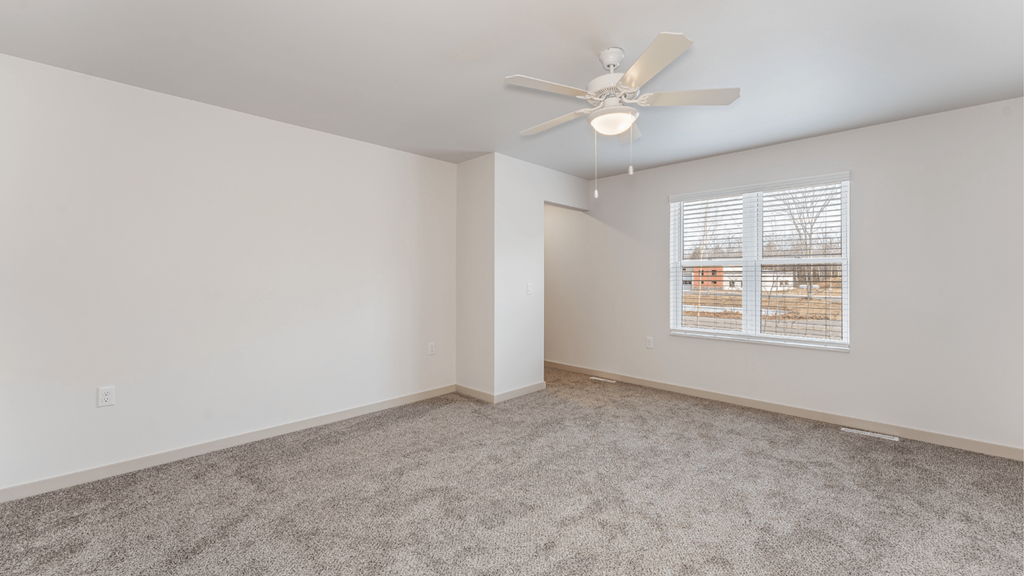 A room with a ceiling fan and a window with blinds.