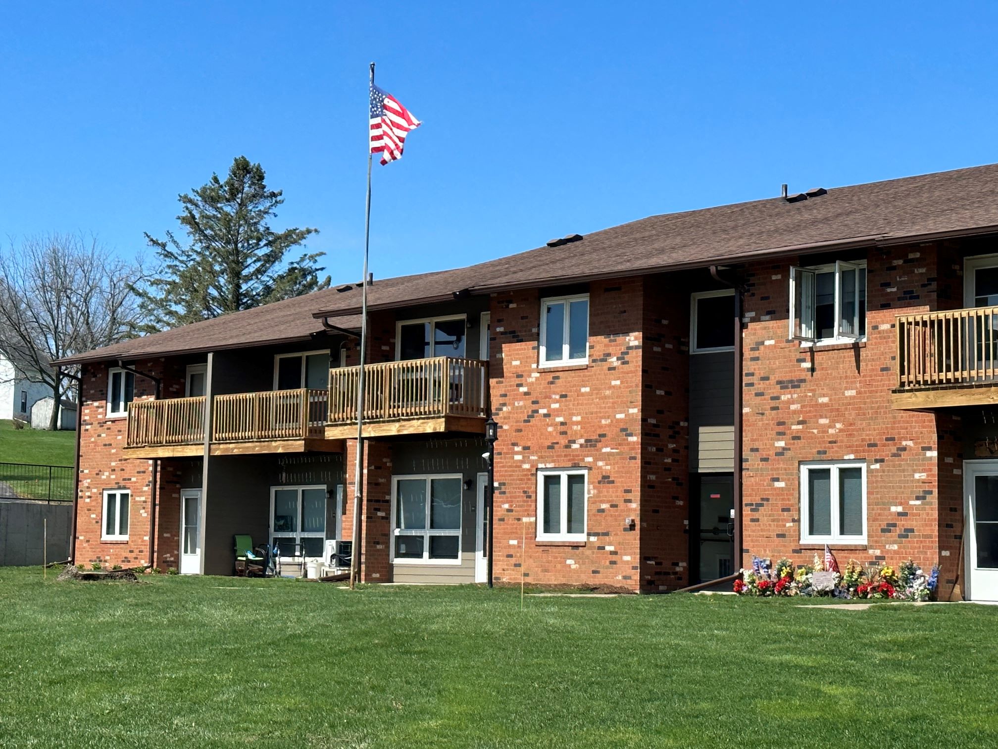 A red brick building with a balcony and an American flag on top.