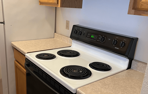A white stove top with four burners and a control panel above it.