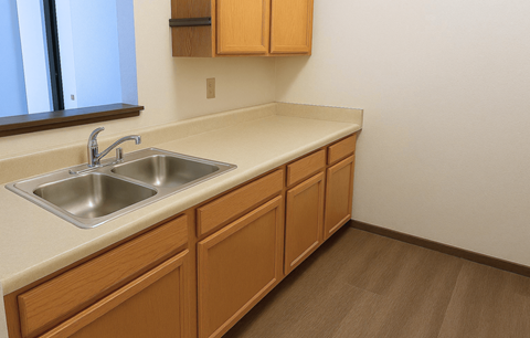 A kitchen with a sink and wooden cabinets.