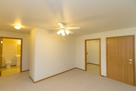 a bedroom with a ceiling fan and a door to a bathroom