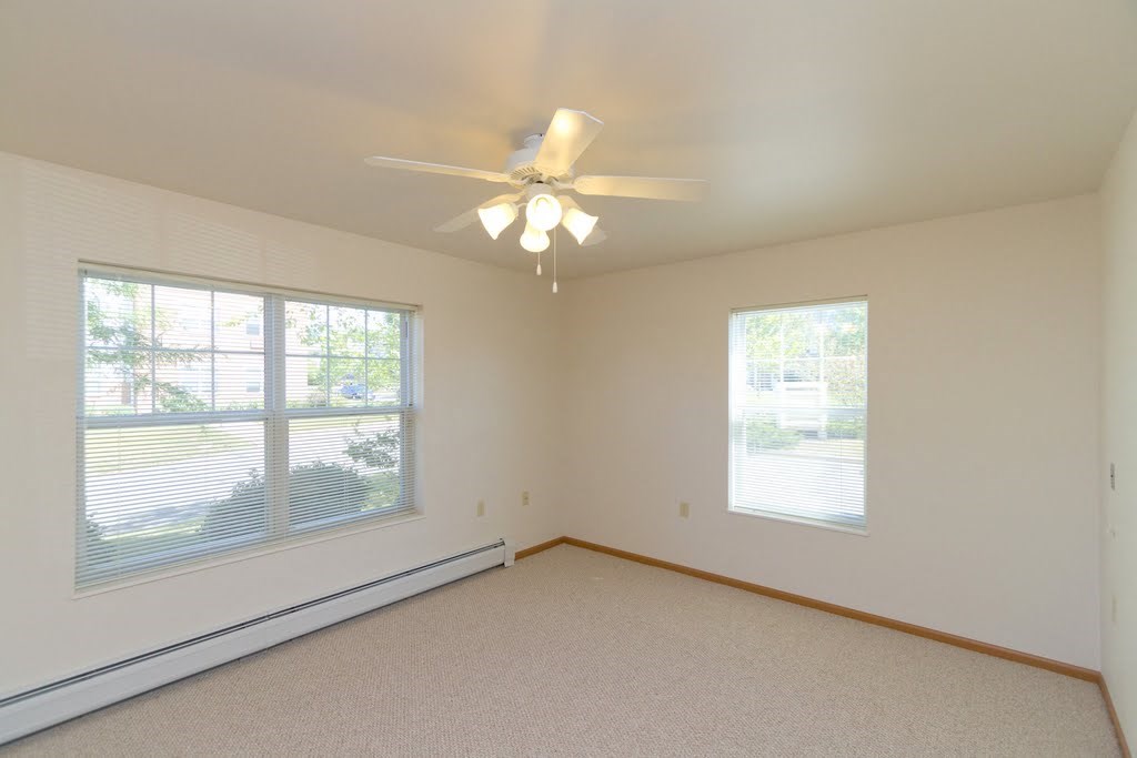 a bedroom with a ceiling fan and two windows