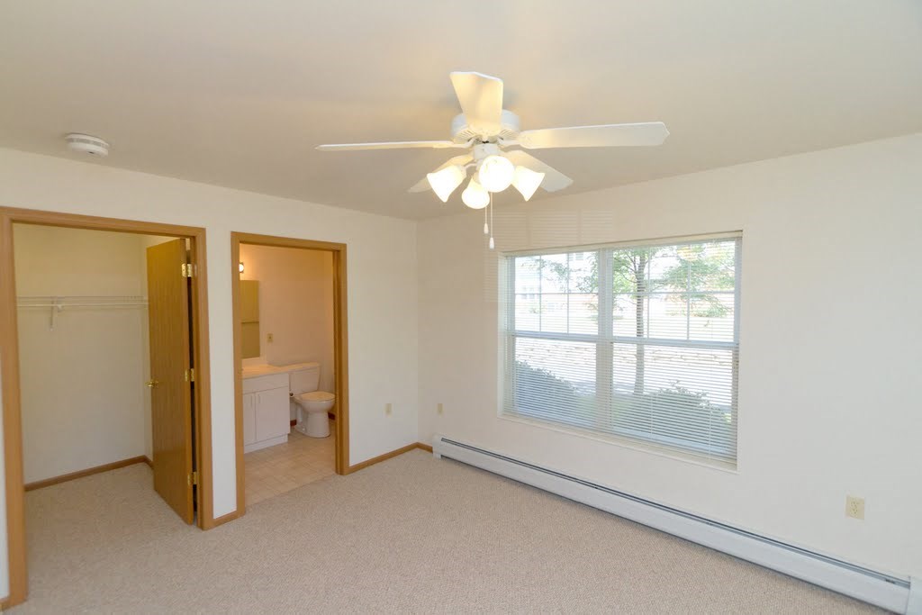 a bedroom with a large window and a ceiling fan