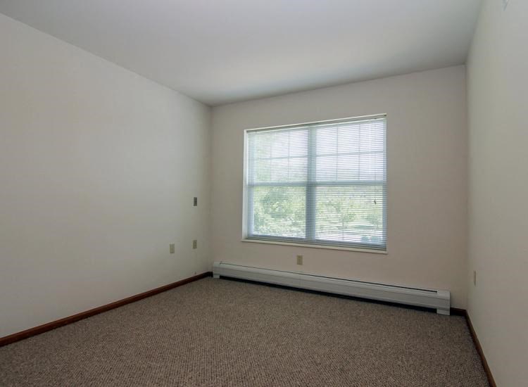 an empty room with a large window and carpet