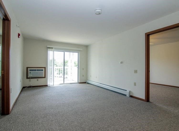 an empty living room with a door to a balcony