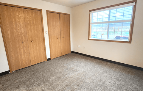 an empty room with a window and two doors