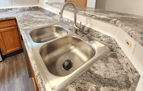 a stainless steel sink in a kitchen with granite countertops