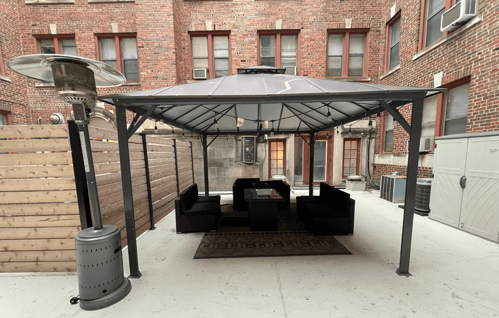 A patio with a black umbrella and a black couch.