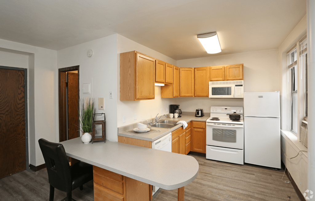 A kitchen with a white refrigerator, white oven, and wooden cabinets.