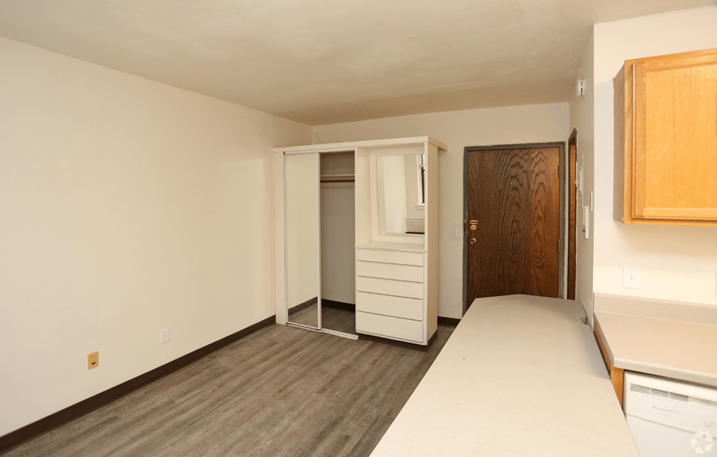 A room with a white bed and a wooden door.