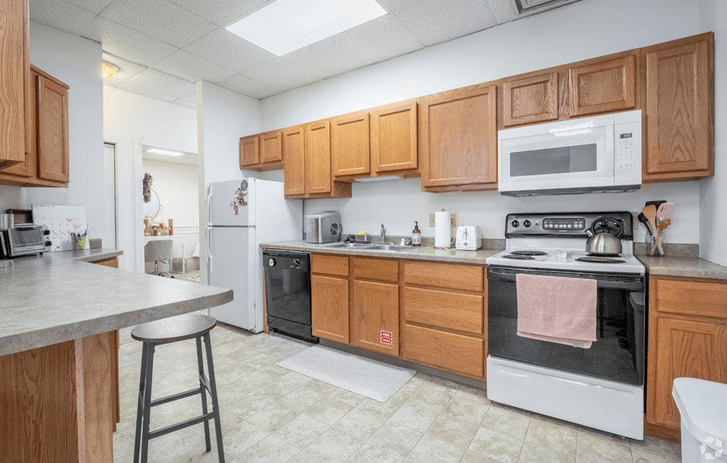 A kitchen with a white stove top oven and a white microwave above it.