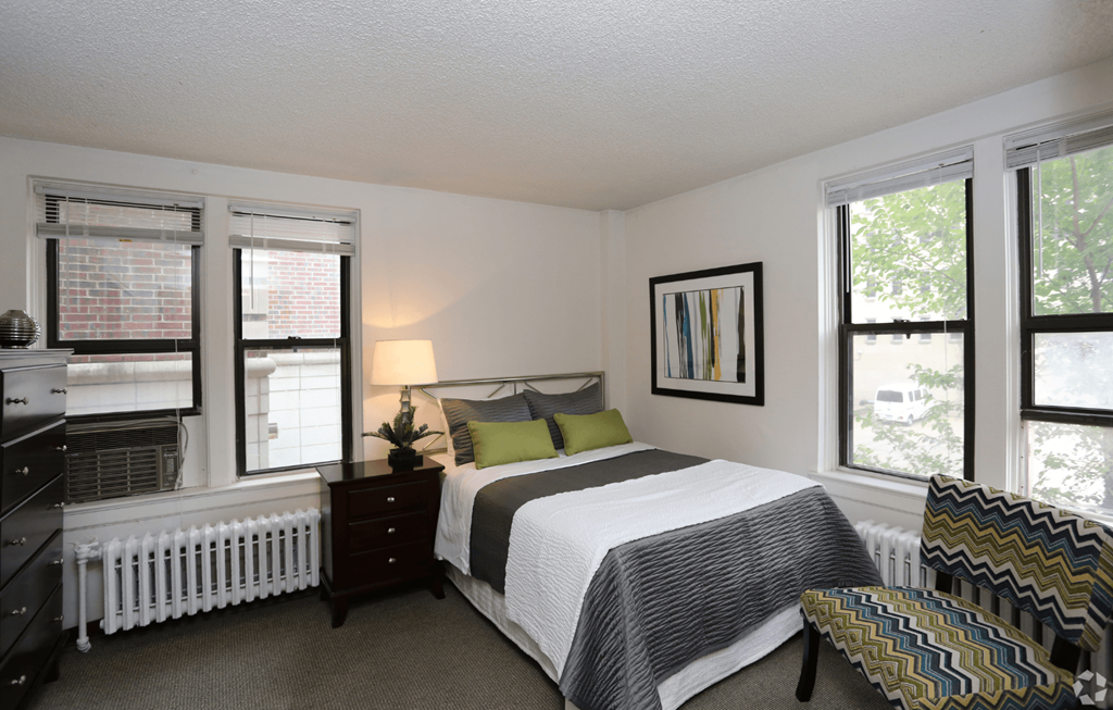 A bedroom with a bed, nightstand, and window.