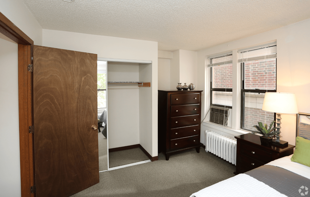 A bedroom with a bed, dresser, and window.