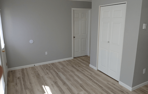 A room with two white doors and wooden flooring.