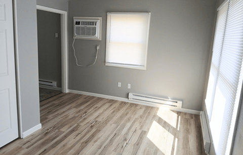 A room with wooden flooring and a window with blinds.