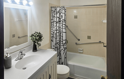 A bathroom with a white sink, a white toilet, a white bathtub, and a white shower curtain.