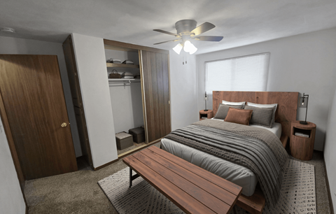 A bedroom with a bed, a bench, and a ceiling fan.