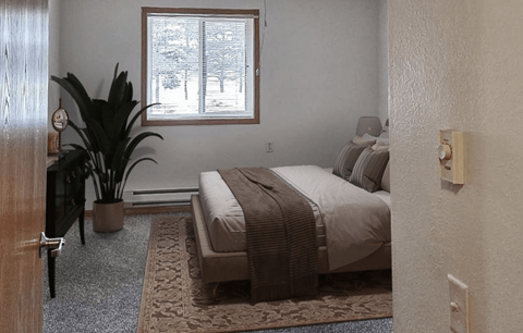 A bedroom with a bed, a potted plant, and a window.