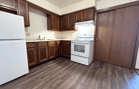 A kitchen with white appliances and brown cabinets.