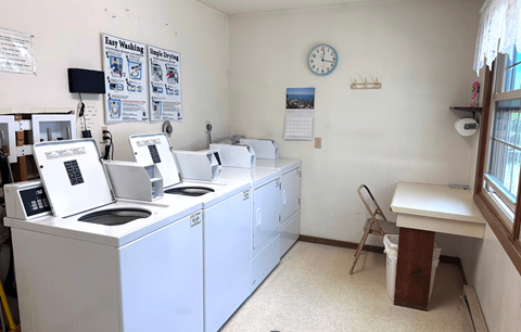 A laundromat with washers and dryers and a clock on the wall.