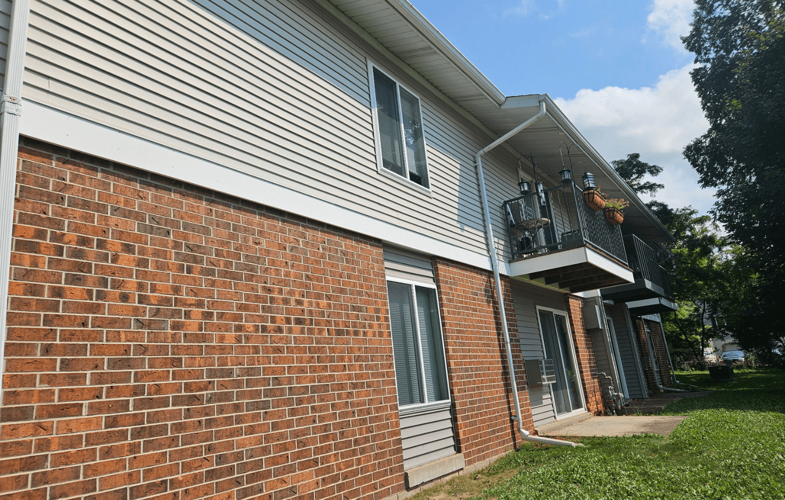 A house with a red brick wall and a grey siding.