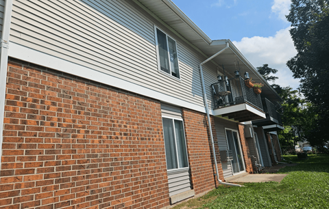 A house with a red brick wall and a grey siding.