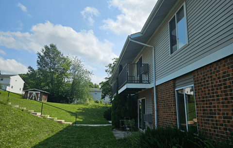 A house with a balcony overlooking a green lawn.