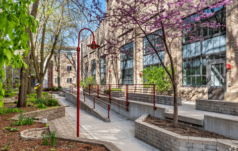 A walkway with red railings and trees in front of a building.