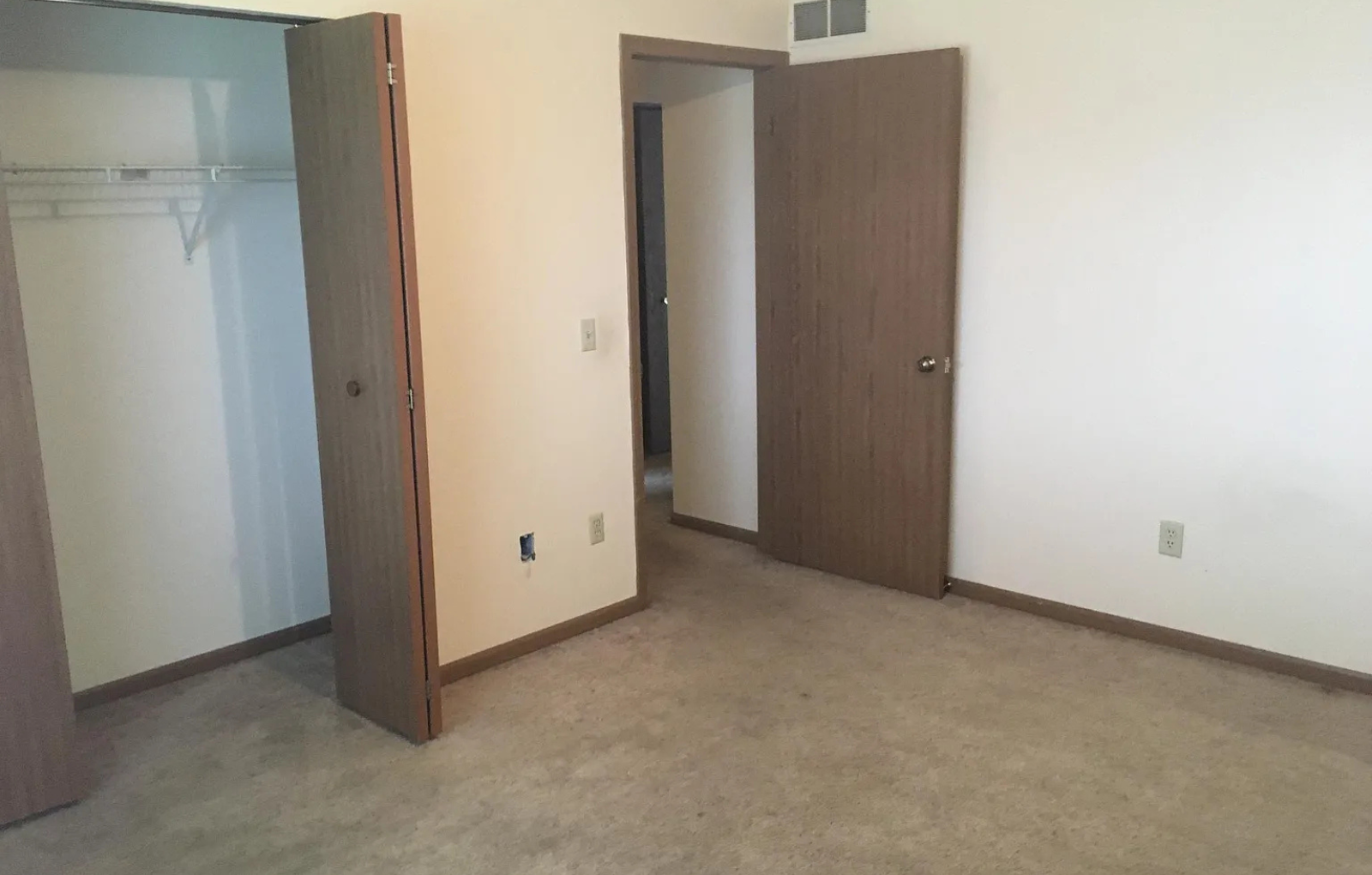 A room with a brown door and a white wall.