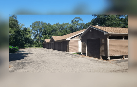 A row of garages are lined up on a gravel lot.