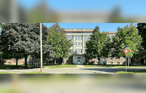 A street view with a building in the background and a yield sign in the foreground.