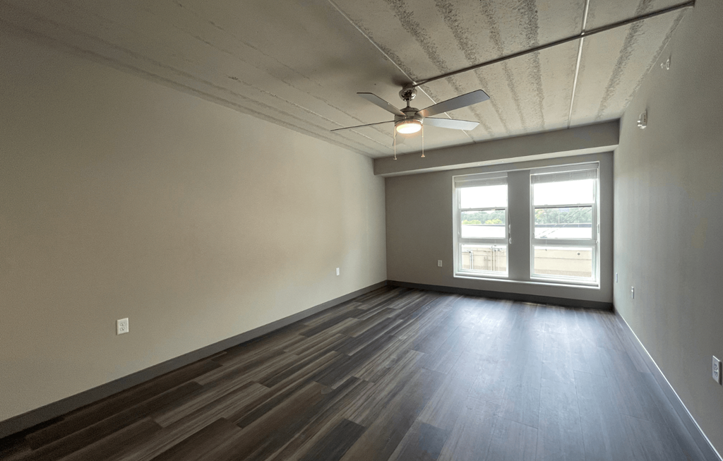 an empty living room with a ceiling fan