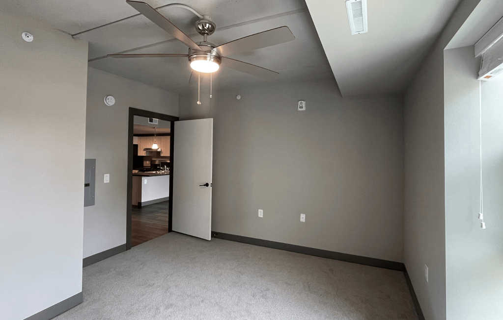 a bedroom with gray walls and a ceiling fan