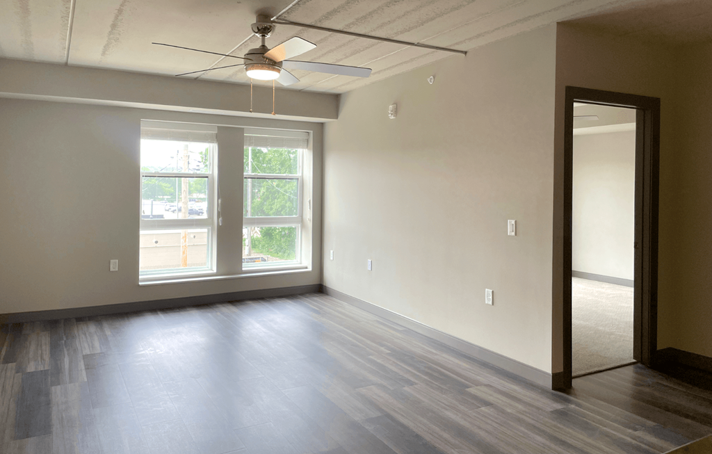 an empty living room with a ceiling fan