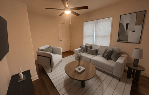 A living room with a grey couch, a coffee table, and a ceiling fan.