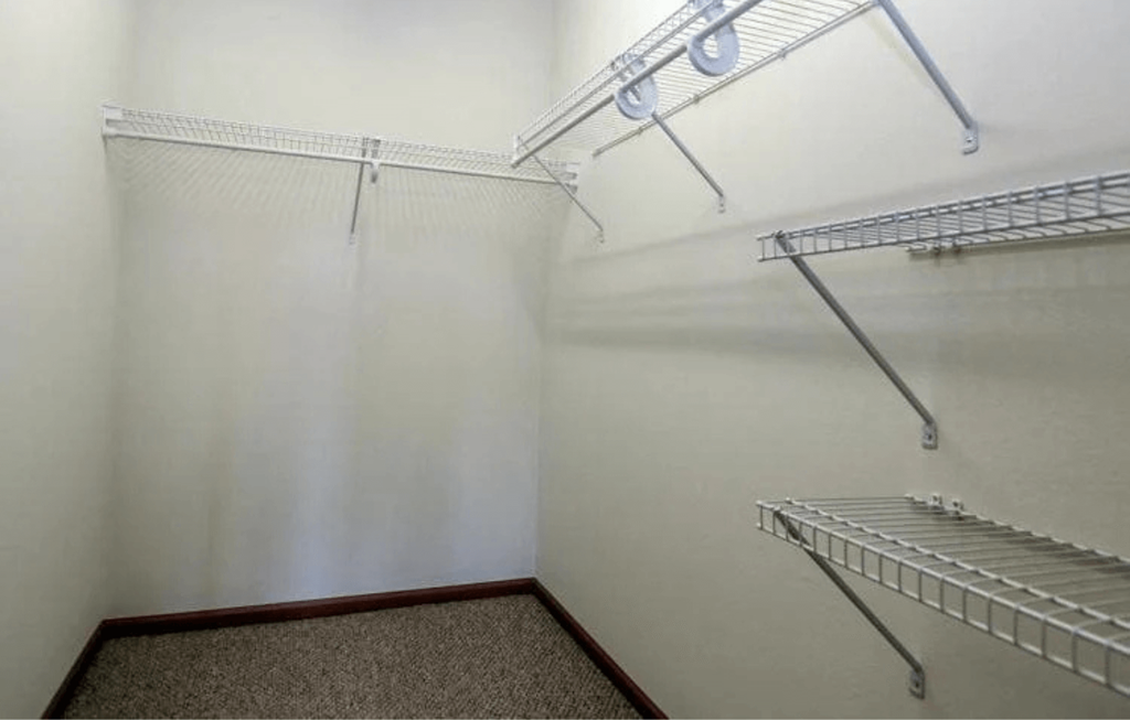 a walk in closet with white walls and two shelves on the wall