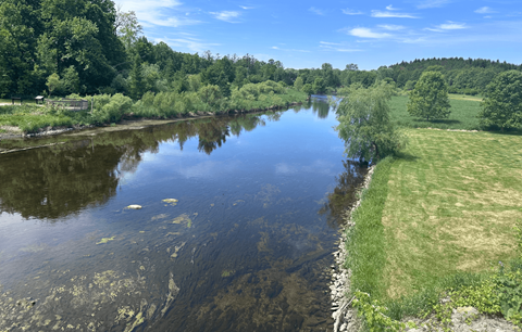 A serene river landscape with a clear reflection of the sky and trees.