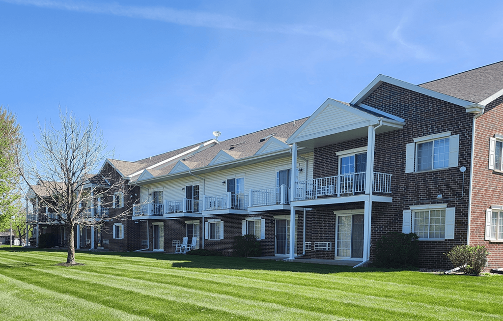 A large brick building with a balcony and a tree in front.
