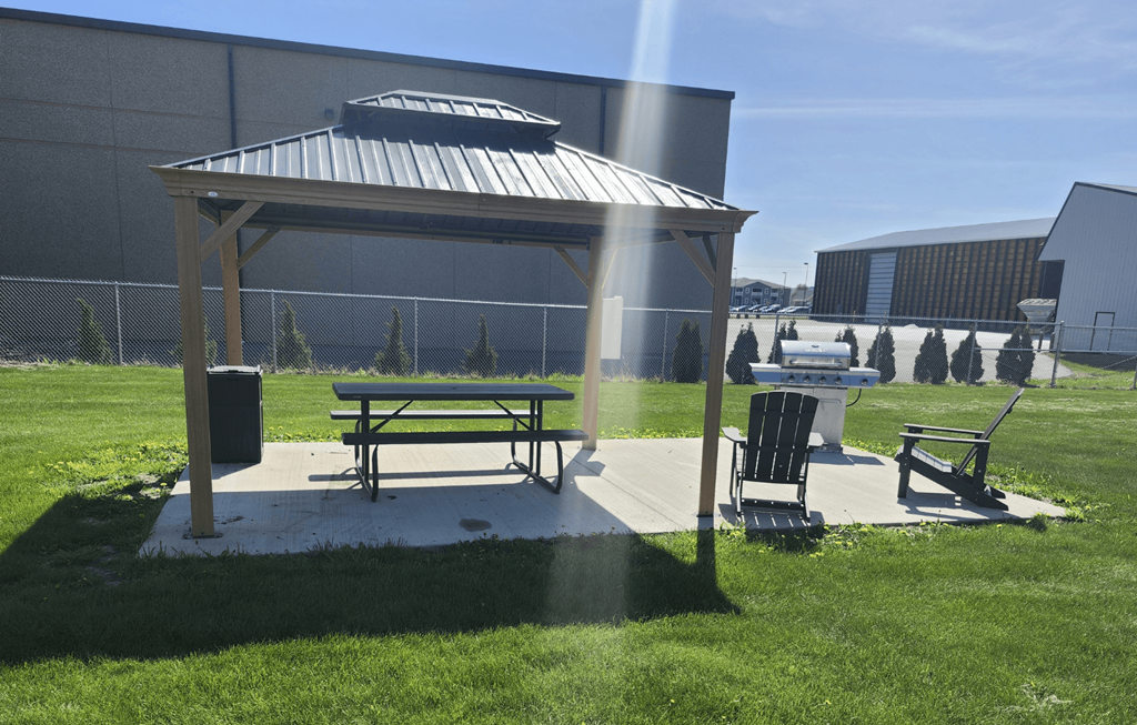 A picnic area with a bench and a table is set up in a grassy area.