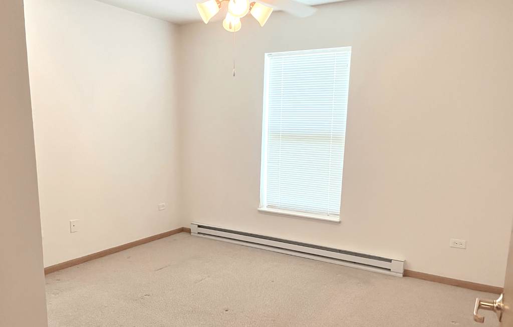 a bedroom with a large window and beige walls