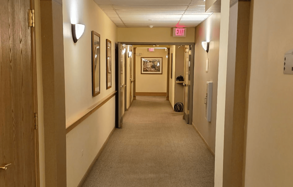 A hallway with a red exit sign at the end.