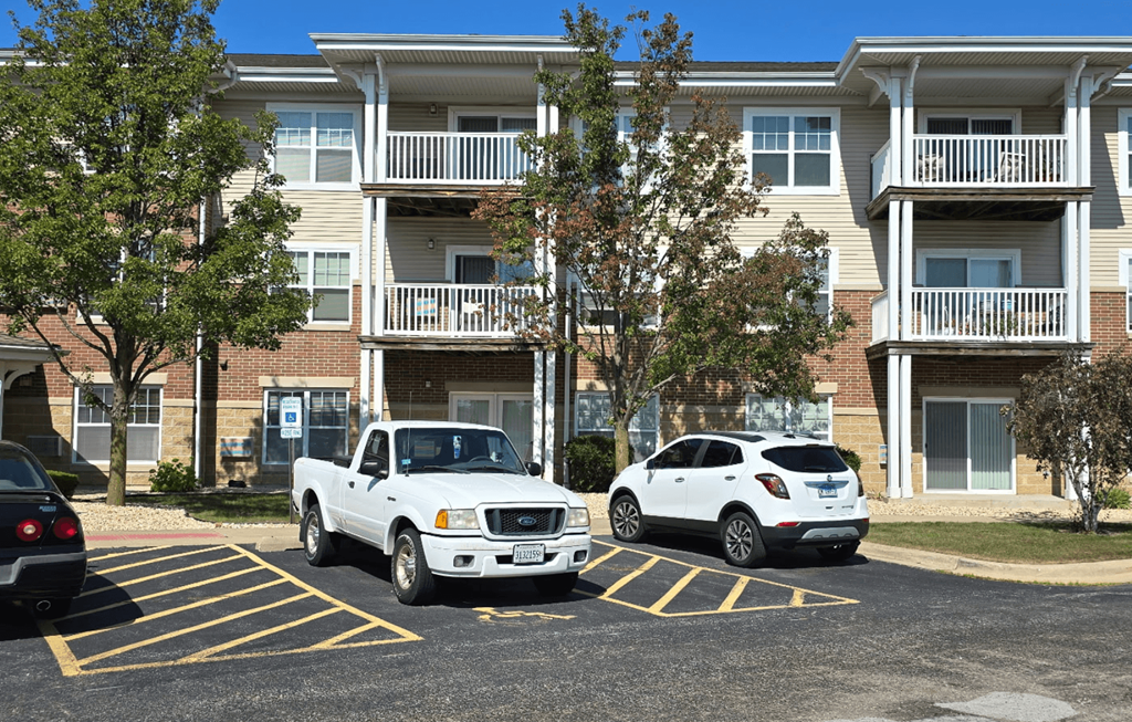 Two cars parked in a parking lot in front of a building.