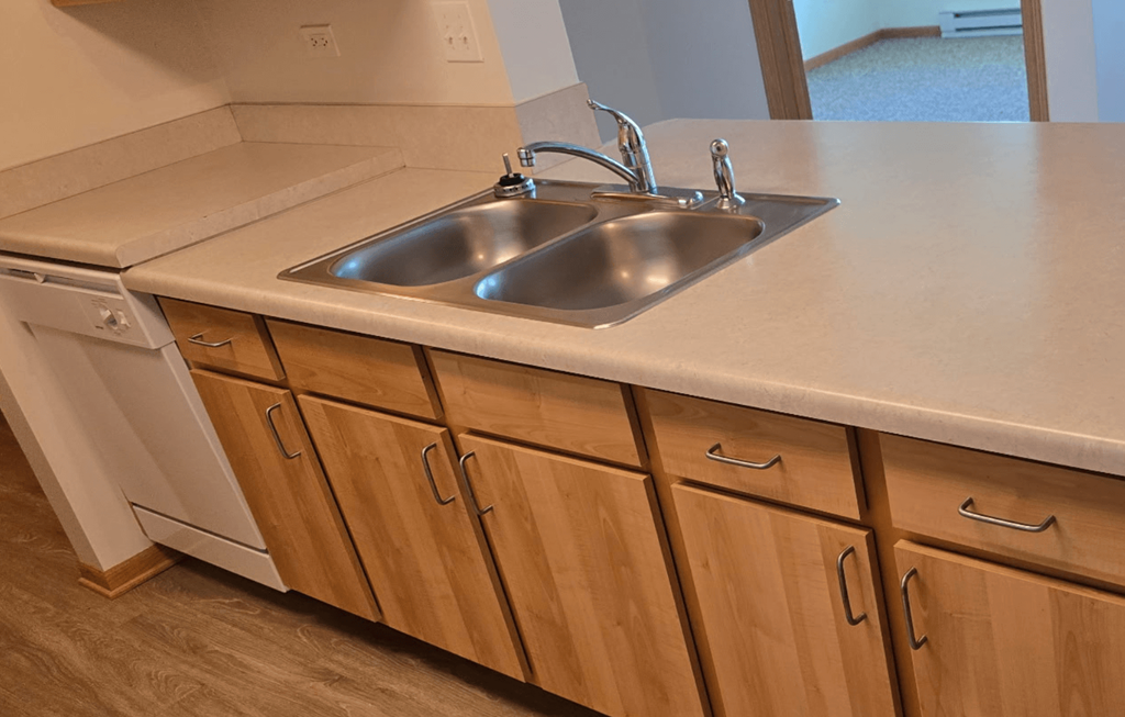 A kitchen with a sink and wooden cabinets.