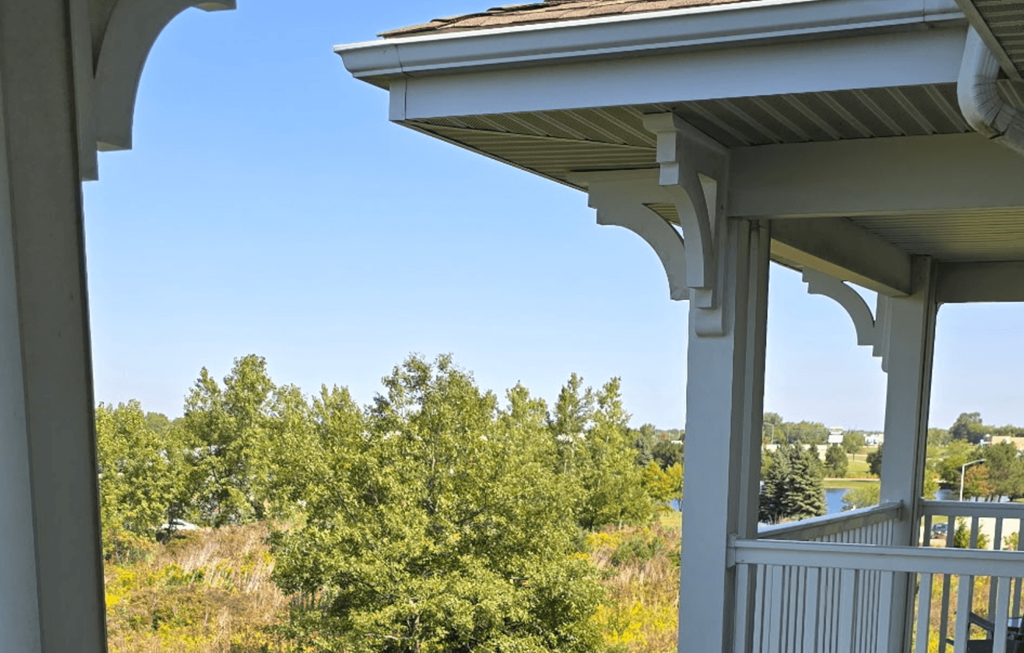 A porch with a view of a field and trees.
